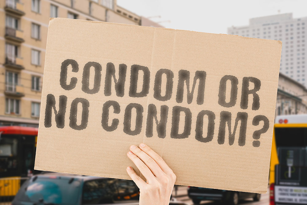 Hand mit Pappkarton und Aufschrift Condom or no Condom