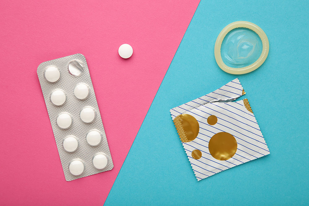 Ein Blister Tabletten und ein Kondom neben der aufgerissenen Verpackung