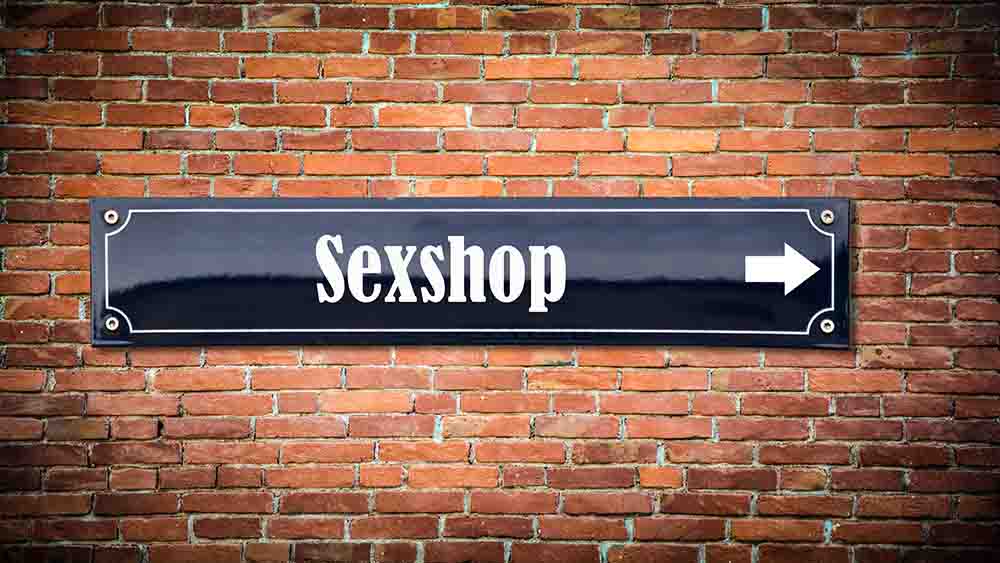 Straßenschild mit Schrift Sexshop auf Ziegelmauer - Thomas Reimer